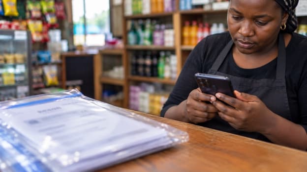 Visual of a lady with physical records while holding her phone
